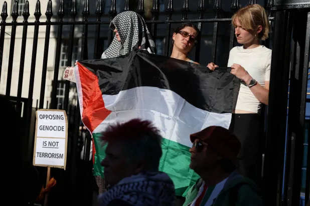 متظاهرون ينظرون خلال احتجاج بعد تصويت المُشرِّعين البريطانيين على حظر جماعة «فلسطين أكشن» المؤيدة للفلسطينيين بوصفها «منظمةً إرهابيةً» خارج «داونينغ ستريت» بلندن في 2 يوليو 2025 (رويترز)