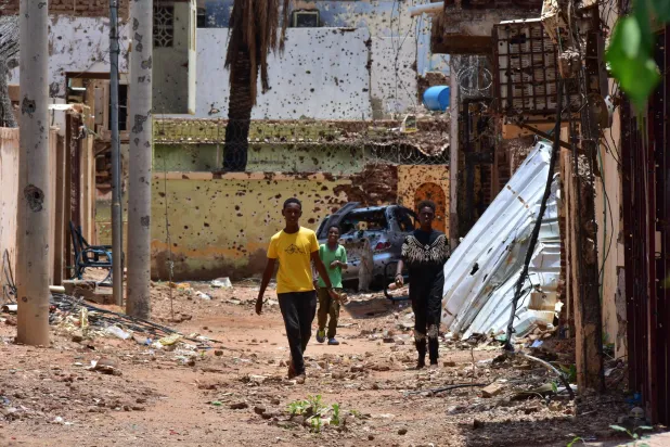 FILED - 27 August 2024, Sudan, Omdurman: Young people walk along a street marked by destruction in Sudan. Photo: Mudathir Hameed/dpa