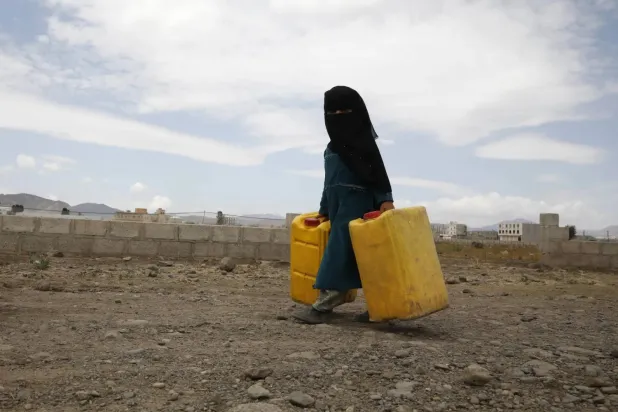 طفلة يمنية تساعد عائلتها في الحصول على المياه في ضواحي صنعاء (إ.ب.أ)