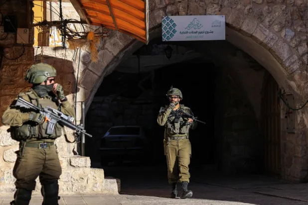 Israeli security forces stand guard as Israeli settlers tour in the Palestinian side of the old city and market of Hebron in the occupied West Bank on July 5, 2025. (Photo by HAZEM BADER / AFP)