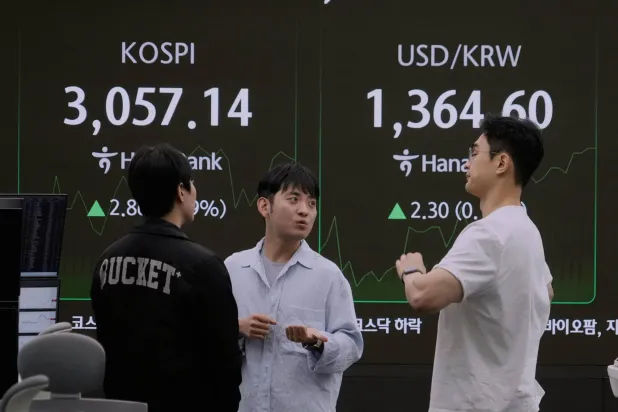 متداولو عملات أمام شاشة مؤشر «كوسبي» وسعر صرف الدولار مقابل الوون في بنك هانا بسيول (أ.ب)