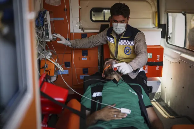 أحد أعضاء فريق الحياة التطوعي في أثناء تلقيه العلاج من استنشاق الدخان خلال مشاركته في جهود إخماد حريق هائل قرب بلدة ربيعة بريف اللاذقية السوري (أ.ب)