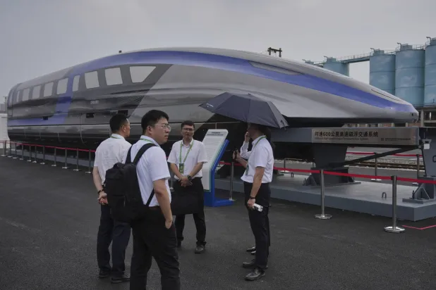 موظفون بالقرب من نموذج قطار مغناطيسي عالي السرعة بمركز اختبار خلال المؤتمر العالمي للسكك الحديدية في العاصمة الصينية بكين (أ.ب)