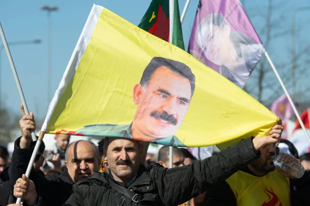 FILED - 02 November 2041, Hesse, Frankfurt_Main: A man displays a flag with the image of imprisoned Kurdish leader Abdullah Ocalan at the Kurdish Newroz celebration in Frankfurt. Photo: Boris Roessler/dpa