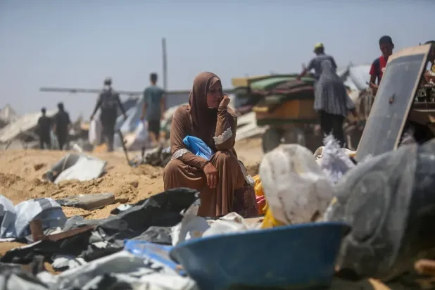 İsrail tanklarının Gazze Şeridi'nin güneyine girmesinin ardından, geçici mülteci kampındaki derme-çatma çadırların arasında enkazın üzerinde oturan bir kadın (AFP)