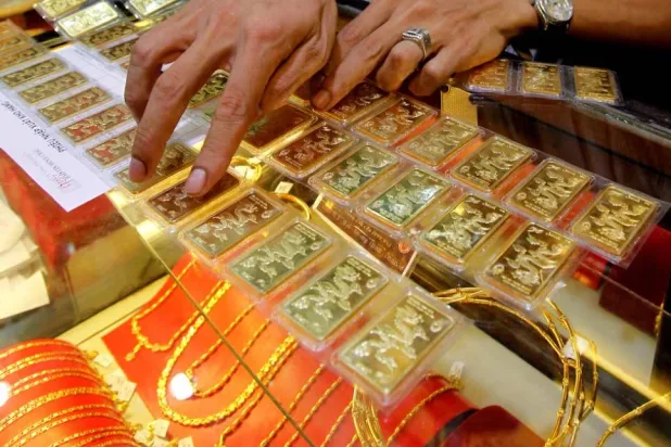 موظف يفحص سبائك ذهبية قبل بيعها لزبون بمتجر في هانوي (رويترز)