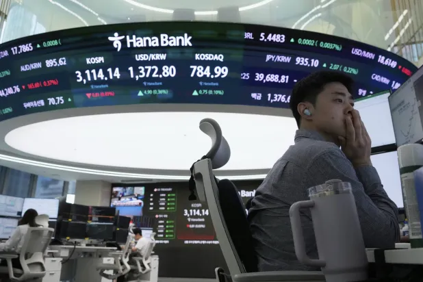 متداول عملات يتابع شاشة تعرض مؤشر «كوسبي» وسعر صرف الدولار مقابل الوون في بنك «هانا» بسيول (أ.ب)