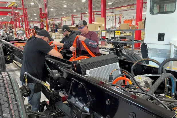 موظفون يركبون كابلات على شاحنة كهربائية في مصنع «باتل موتورز» بأوهايو (رويترز)