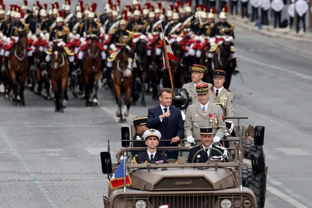 France's President Emmanuel Macron (center-L) and France's Chief of the Defense Staff General Thierry Bukhard (center-R) and French Military Governor of Paris (GMP) Loic Mizon (center-Top) review troops as they stand in the command car flanked by France's mounted Republican Guard (Guarde Republicaine) during the annual Bastille Day military parade on the Champs-Elysees Avenue in Paris on July 14, 2025. (Photo by Ludovic MARIN / AFP)