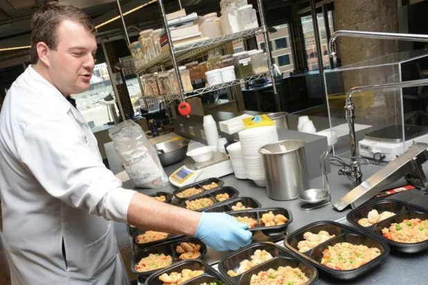 عامل في مطبخ يجهز وجبات معلبة (رويترز)