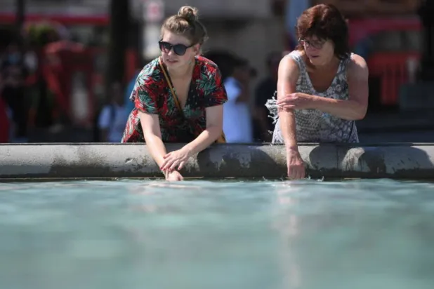 سيدتان تحاولان التبريد بالقرب من الماء وسط درجات الحرارة المرتفعة في لندن (إ.ب.أ)