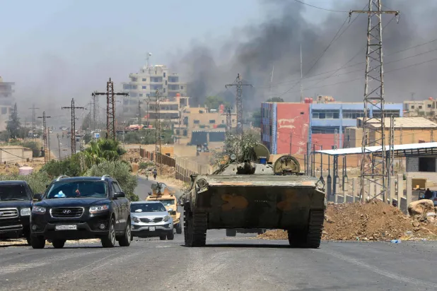 أفراد من قوات الأمن السورية يعبرون بمركباتهم في مدينة السويداء ذات الأغلبية الدرزية في 15 يوليو 2025 بينما يتصاعد الدخان في أعقاب قصف إسرائيلي أعقب الاشتباكات بين القبائل البدوية والمقاتلين الدروز (أ.ف.ب)