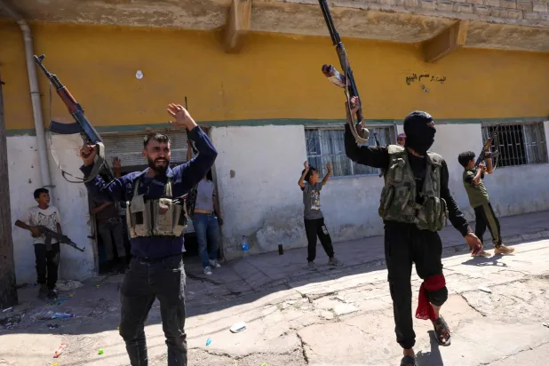 أفراد من قوات الأمن السورية وأطفال يحملون بنادق في أحد أحياء السويداء 15 يوليو 2025 (أ.ف.ب)