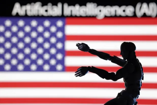 نموذج مصغر لروبوت أمام علم الولايات المتحدة ومكتوب أعلاه «الذكاء الاصطناعي» (رويترز)