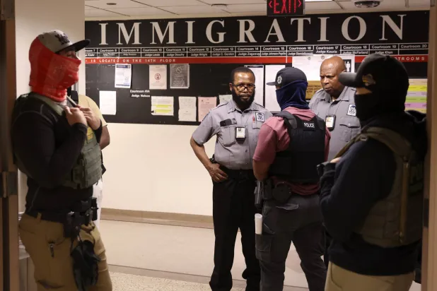 عملاء فيدراليون يتحدثون مع عناصر الأمن في إحدى محاكم الهجرة بنيويورك (إ.ب.أ)