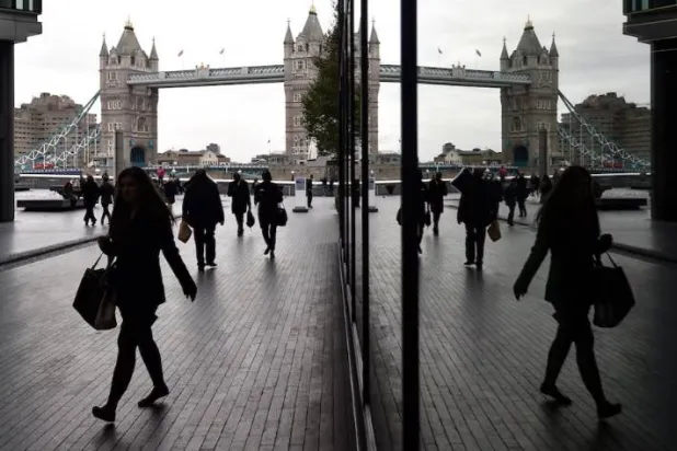 يمشي موظفون بمنطقة «مور لندن» التجارية حيث يظهر جسر «البرج» الشهير في الخلفية (أرشيفية - رويترز)

