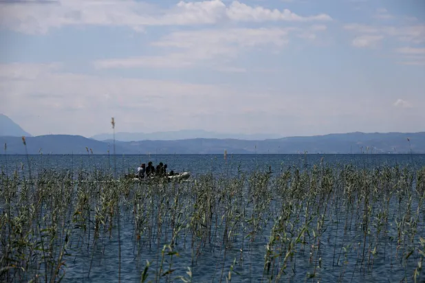 فريق من علماء الآثار يبحرون في بحيرة أوهريد بقرية لين الألبانية (رويترز)
