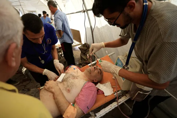 رجل فلسطيني مصاب يتلقى الرعاية الطبية بمستشفى الأهلي العربي بعد غارة إسرائيلية على كنيسة العائلة المقدسة (رويترز)