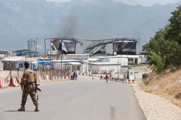 مسؤول أمني يقف بالقرب من موقع حقل نفطي بعد هجوم بطائرة مسيرة في محافظة دهوك بالعراق (رويترز)