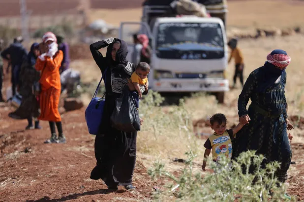 نساء وأطفال يسيرون في منطقة بين درعا والسويداء بسوريا بعد مقتل عشرات في أحداث عنف هذا الأسبوع (رويترز)