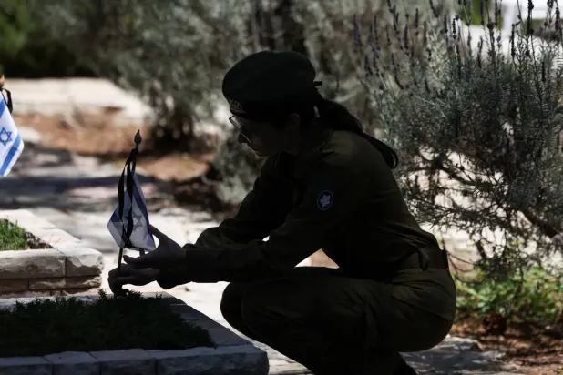 Geçtiğimiz nisan ayında Kudüs'teki askeri mezarlıkta bir askerin mezarına bayrak diken İsrail askeri (Reuters)