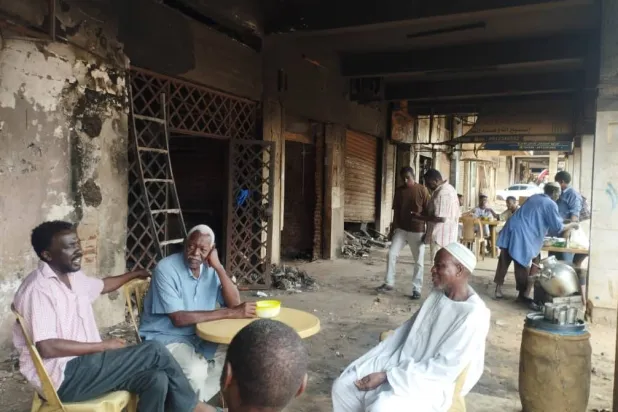 تجار يجتمعون أمام متاجرهم المحترقة في إحدى الصالات التجارية بالخرطوم (خاص)