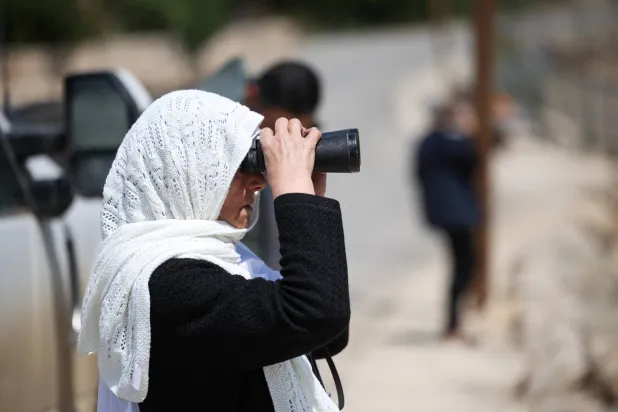 سيدة درزية من الجولان المحتل تنظر عبر الحدود باتجاه سوريا (رويترز)