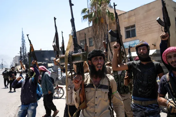 مقاتلون من العشائر البدوية ينتشرون في بلدة المزرعة ذات الأغلبية الدرزية في ريف السويداء (إ.ب.أ)