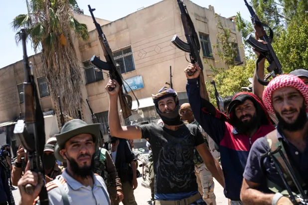 مقاتلون من العشائر البدوية ينتشرون في بلدة المزرعة ذات الأغلبية الدرزية بريف السويداء (إ.ب.أ)