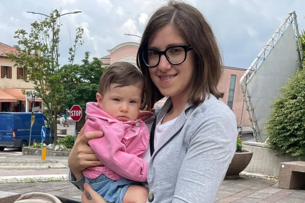 المواطنة الإيطالية من القرية فالنتينا دوتور حيث تحمل ابنتها ديليتا البالغة من العمر 10 أشهر (بي بي سي)