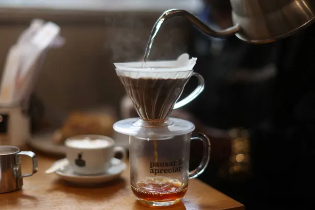 نادلة تقوم بصنع كوب من القهوة في البرازيل (رويترز)