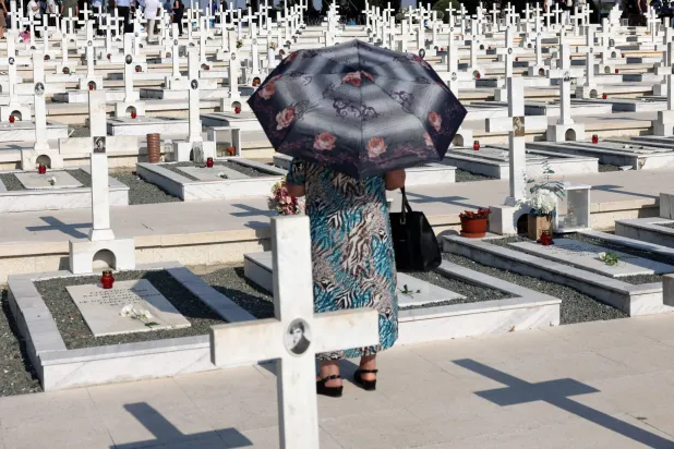 A woman walks next to the graves of soldiers killed in the 1974 Turkish invasion of Cyprus at the Tymvos Makedonitissas military cemetery in Nicosia, Cyprus July 20, 2025. REUTERS/Yiannis Kourtoglou
