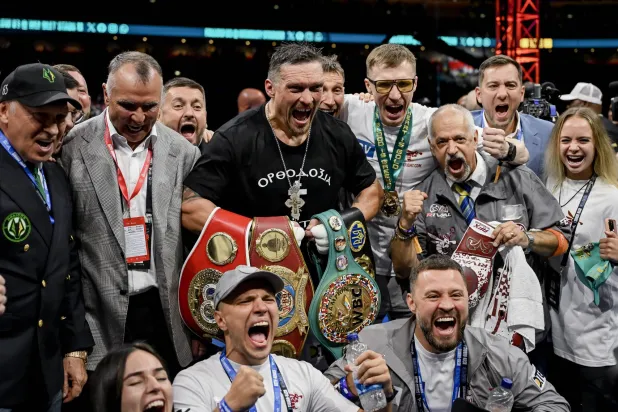 الأوكراني أولكسندر أوسيك (وسط) يحتفل مع فريقه بعد أن أسقط البريطاني دانييل دوبوا بالضربة القاضية خلال نزال لقب العالم الموحد للوزن الثقيل (إ.ب.أ)
