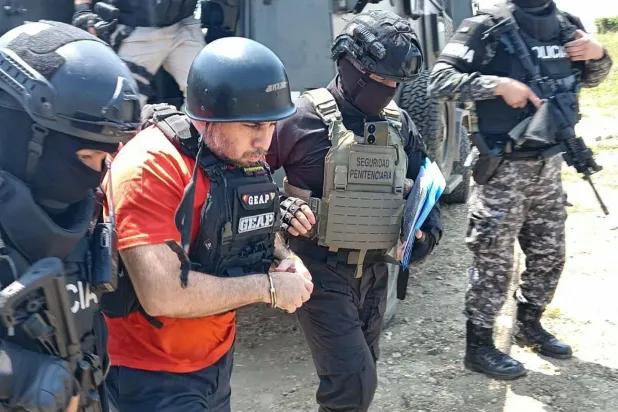 زعيم عصابة المخدرات أدولفو ماسياس أثناء اقتياده خارج سجن لا روكا لتسليمه إلى الولايات المتحدة في غواياكيل أمس (أ.ف.ب)