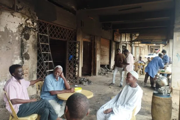 تجار يجتمعون أمام متاجرهم المحترقة في إحدى الصالات التجارية بالخرطوم (الشرق الأوسط)