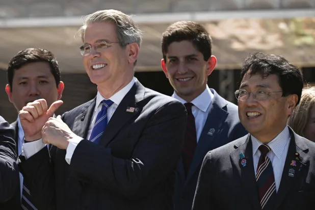 وزير الخزانة سكوت بيسنت يُلوِّح بيده خلال وقوفه مع وزير الإنعاش الاقتصادي الياباني وكبير المفاوضين التجاريين ريوسي أكازاوا في أوساكا (إ.ب.أ)