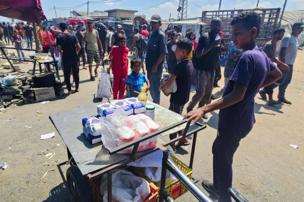 فلسطينيون يتطلعون بأنظارهم إلى أجولة طحين معروضة للبيع بمنطقة المواصي برفح يوم الأحد (أ.ف.ب)