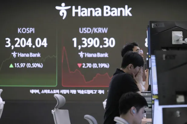 متداول عملات يتابع مؤشر «كوسبي» وسعر صرف الدولار مقابل الوون في مقر بنك هانا بسيول (أ.ب)