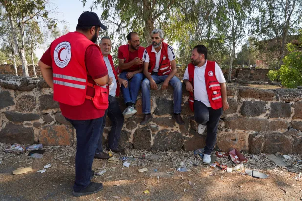 أعضاء الهلال الأحمر العربي السوري ينتظرون دخول السويداء الاثنين حيث تم إجلاء مئات المدنيين البدو (رويترز)