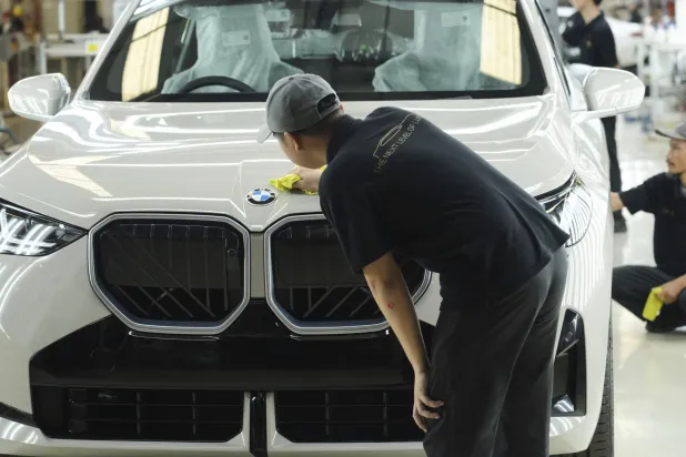 عمال ينظفون سيارة «بي إم دبليو» في شبكة إنتاج «بي إم دبليو-2» بمصنع في جاكرتا (أ.ب)