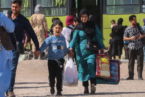 حافلة إيرانية تُنزل لاجئين أفغان عند نقطة الصفر على حدود إسلام قلعة في ولاية هرات الخميس (أ.ف.ب)