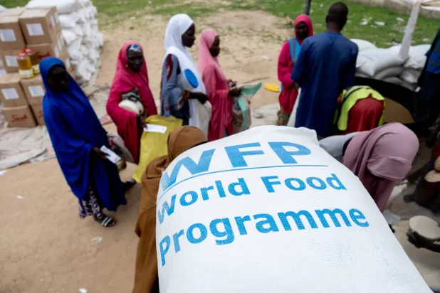 مستفيدون يصطفون لتلقي الدعم داخل مركز توزيع تابع لـ«برنامج الأغذية العالمي» في دامبوا بولاية بورنو النيجيرية يوم 20 يوليو 2025 (رويترز)