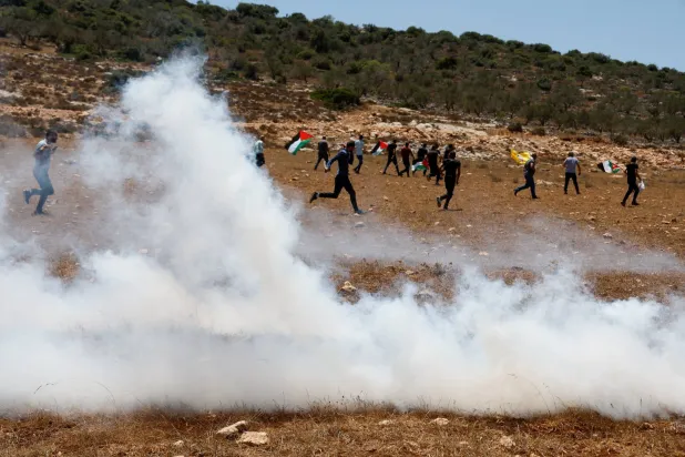 فلسطينيون وسط الغاز المسيل للدموع خلال مظاهرة احتجاج يوم الجمعة الماضي على مصادرة أرضهم في قرية رابا قرب جنين (رويترز)