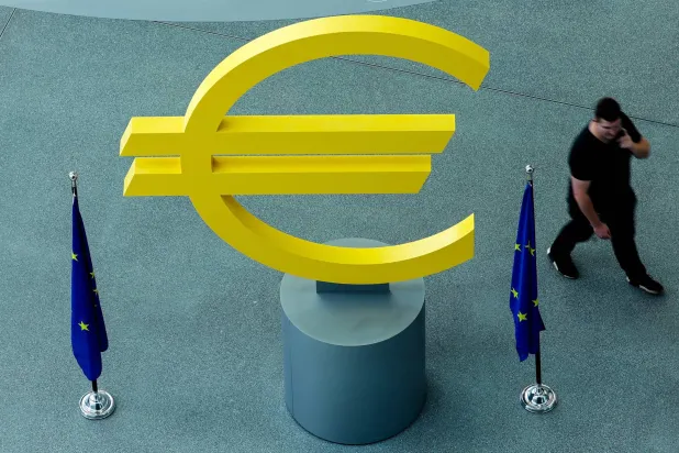 مجسم لعلامة العملة الأوروبية الموحدة وأعلام منطقة اليورو أمام مقر البنك المركزي الأوروبي في مدينة فرانكفورت الألمانية (إ.ب.أ)