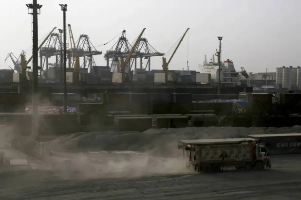 شاحنة تمر أمام رافعات في ميناء كراتشي (رويترز)