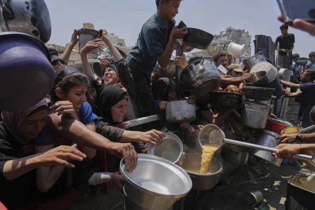 فلسطينيون يكافحون للحصول على الطعام المتبرع به في تكية شمال القطاع مدينة غزة (أ.ب)