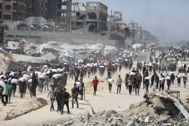 فلسطينيون يحملون أكياس المساعدات الإنسانية في قطاع غزة (د.ب.أ)