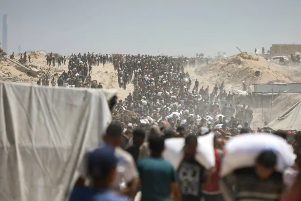 27 July 2025, Palestinian Territories, Gaza City: Palestinians carry sacks of flour from a humanitarian aid convoy, as they make their way along al-Rashid street. Photo: Omar Ashtawy/APA Images via ZUMA Press Wire/dpa
