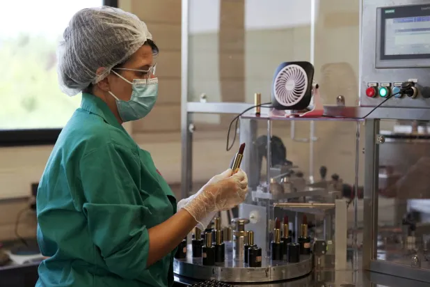 موظفة تفحص أحمر الشفاه أثناء التعبئة في مصنع ينتج إحدى العلامات التجارية في فرنسا (رويترز)
