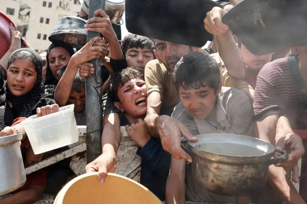 أطفال فلسطينيون يكافحون من أجل الحصول على الطعام في إحدى التكيات بمدينة غزة (رويترز)